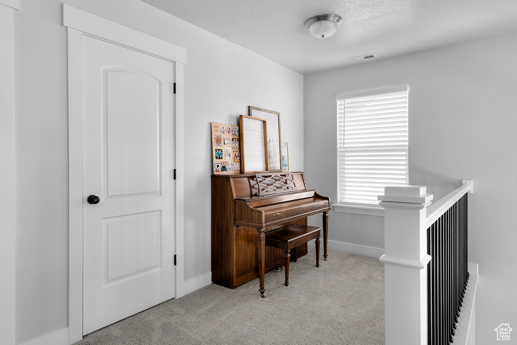 Living area with carpet flooring, an upstairs landing, a textured ceiling, and baseboards