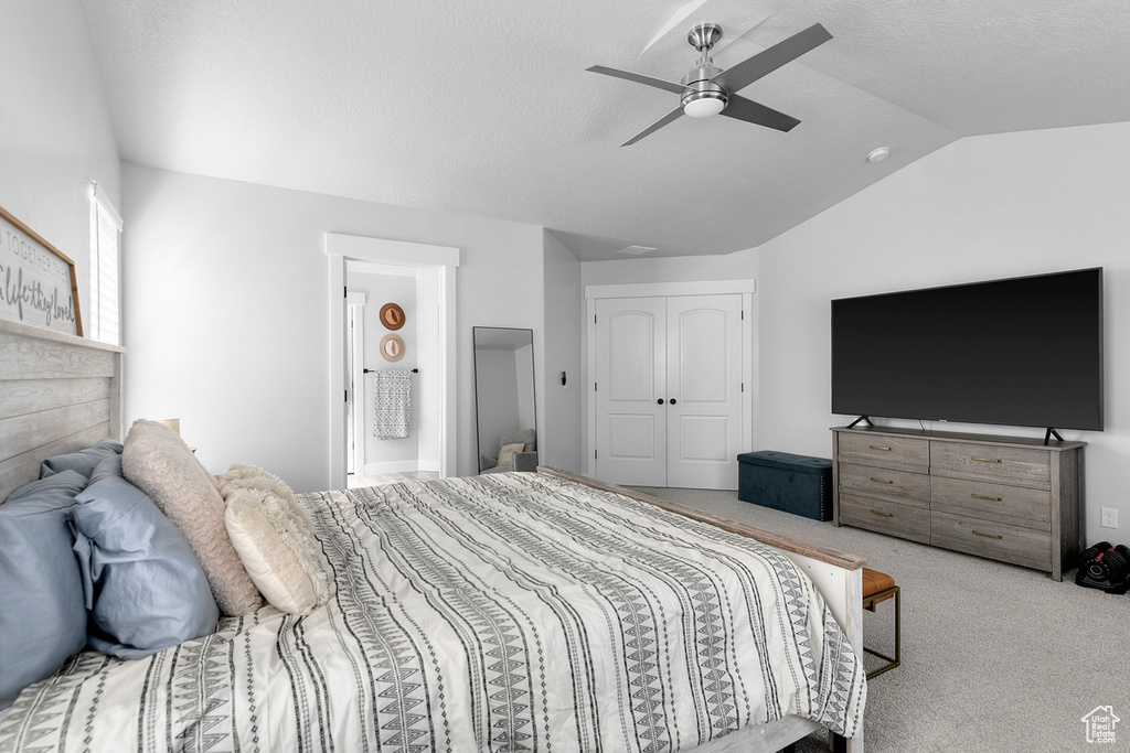Carpeted bedroom featuring vaulted ceiling, a closet, and a ceiling fan