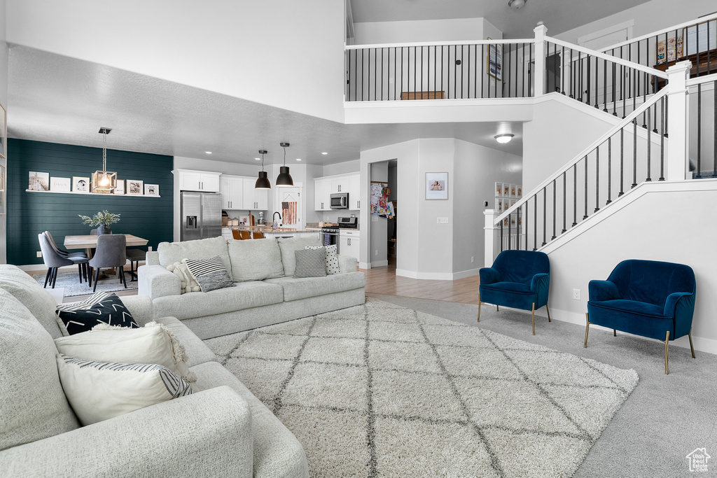 Living area featuring stairway, baseboards, a high ceiling, light colored carpet, and recessed lighting
