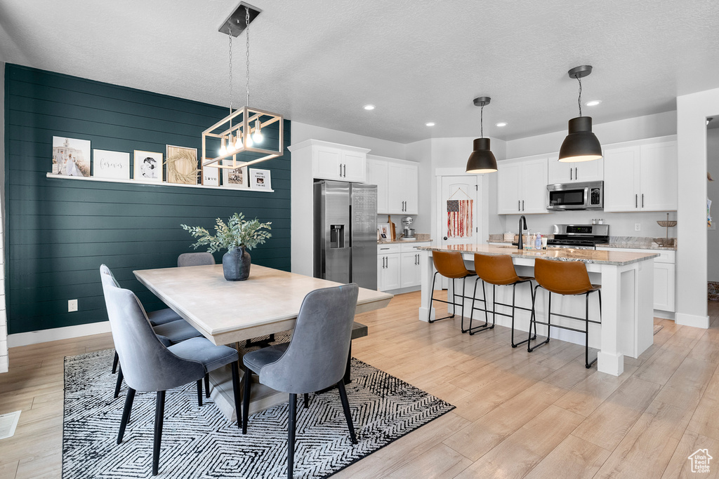 Dining area featuring light wood-style floors, recessed lighting, a chandelier, baseboards, and a textured ceiling