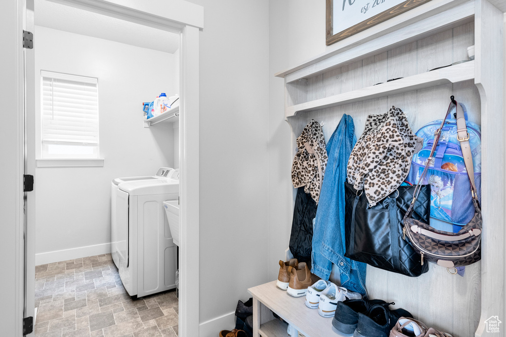 Laundry room featuring stone finish flooring, baseboards, and washer and clothes dryer