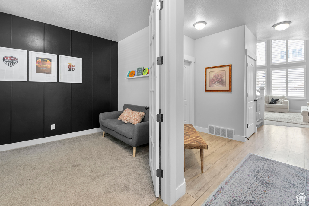 Hall featuring wood finished floors, a textured ceiling, and baseboards
