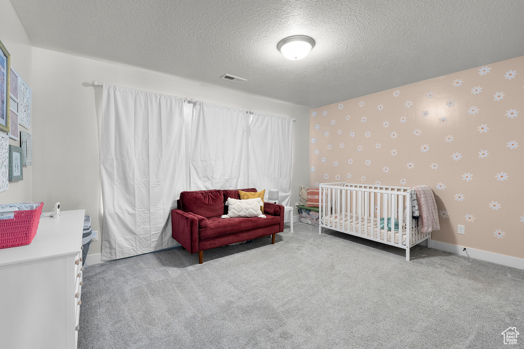 Bedroom with wallpapered walls, a textured ceiling, carpet flooring, and baseboards