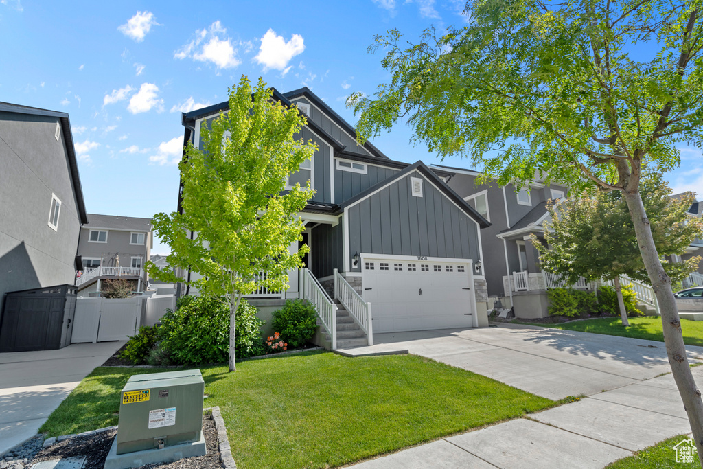 View of front of property featuring board and batten siding, concrete driveway, an attached garage, and a residential view