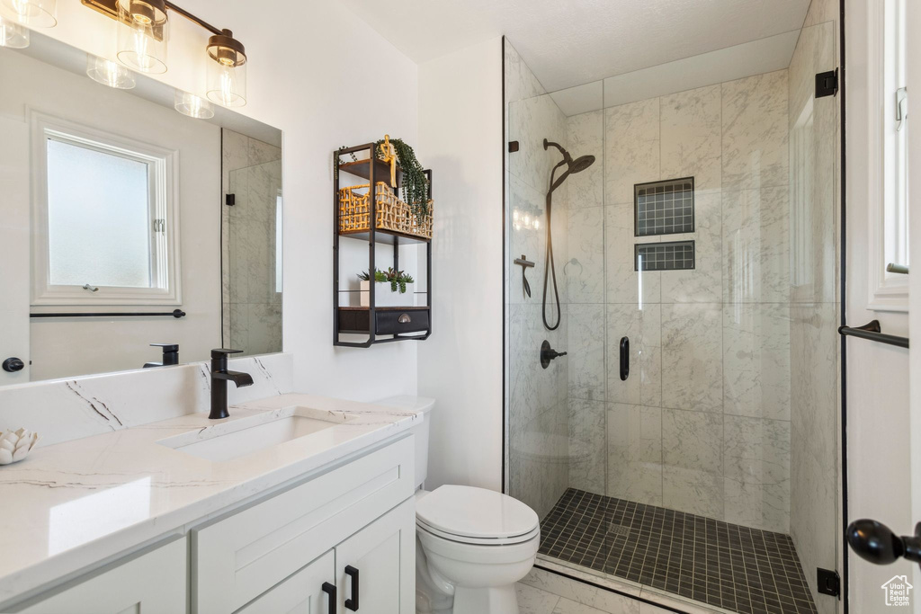 Bathroom featuring vanity, toilet, a stall shower, and marble look tiles