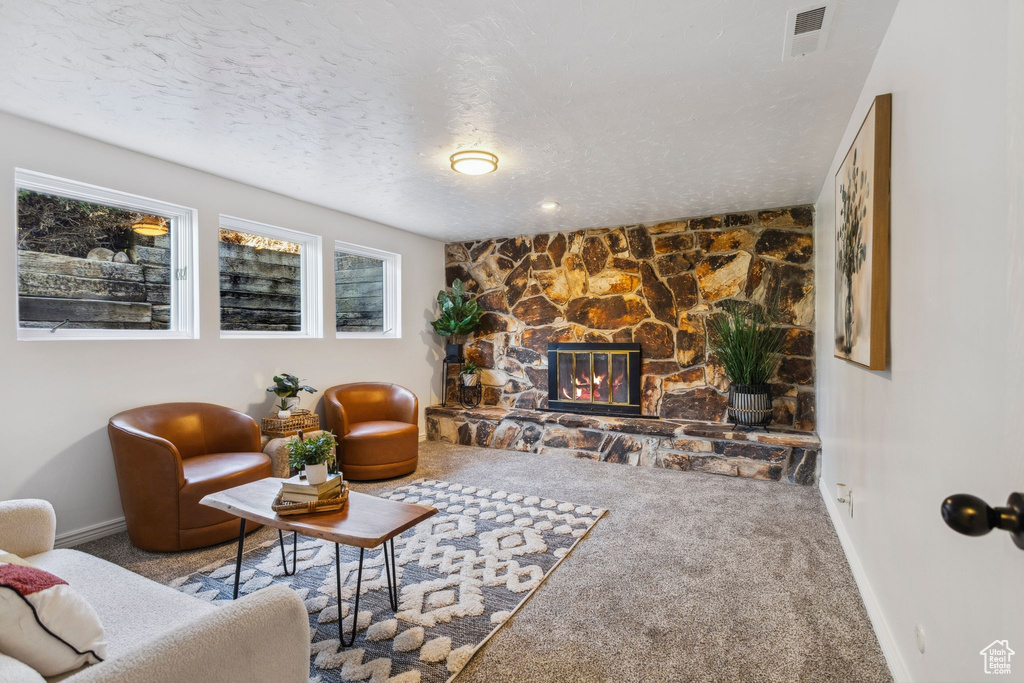 Living room featuring carpet, baseboards, a fireplace, and a textured ceiling