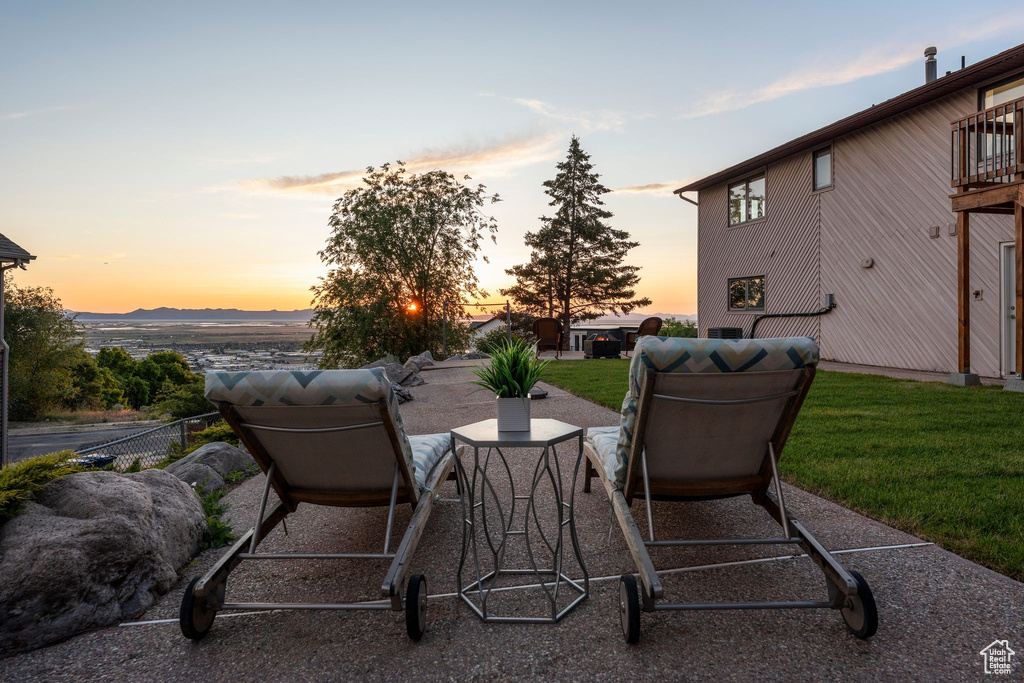 Patio terrace at dusk featuring a yard