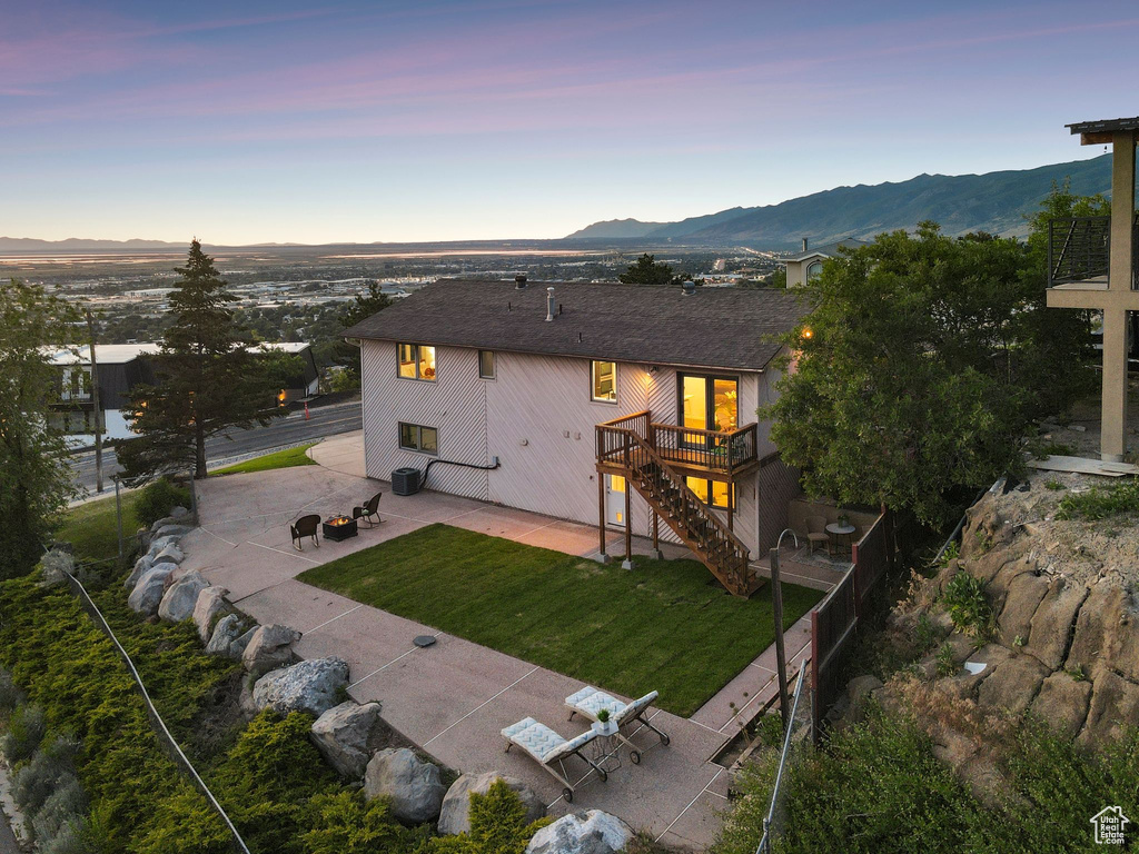 Rear view of property featuring a patio, stairs, a deck with mountain view, a yard, and an outdoor fire pit