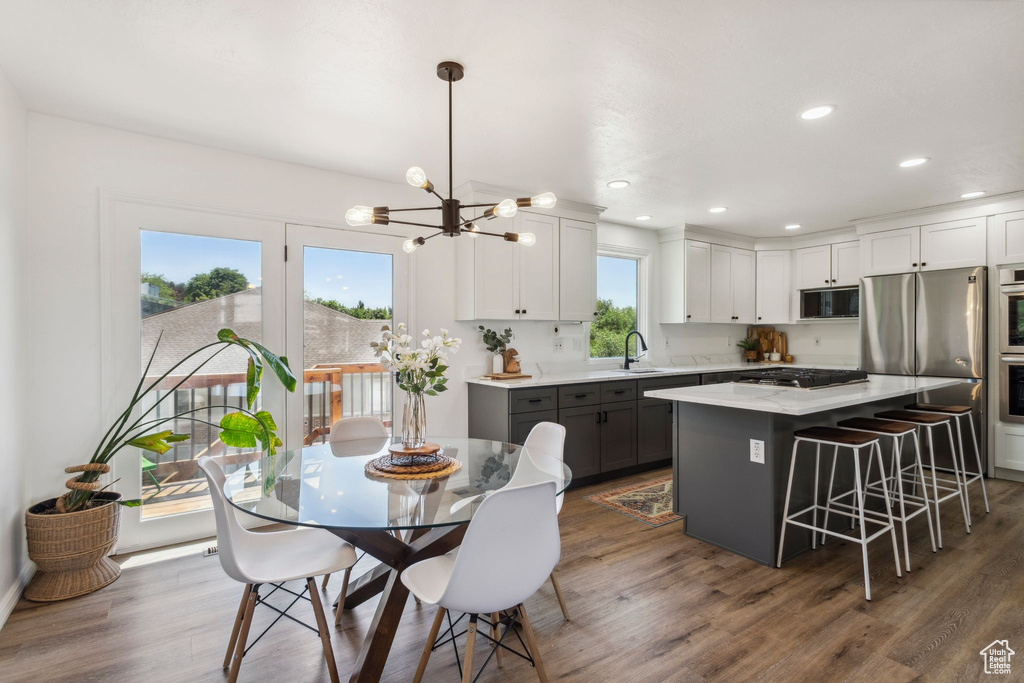 Kitchen with appliances with stainless steel finishes, a sink, light countertops, dark wood finished floors, and a chandelier