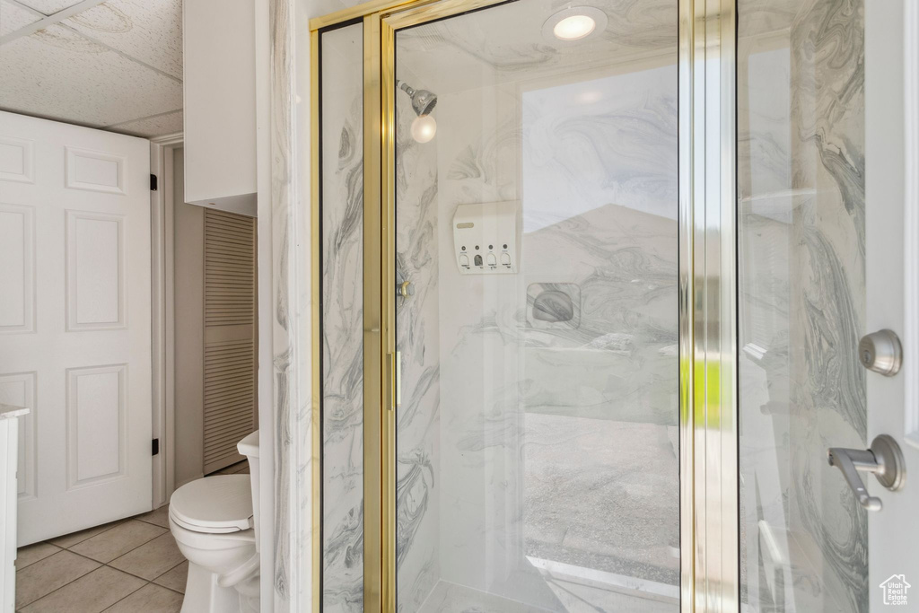 Bathroom with a marble finish shower, tile patterned floors, toilet, and a closet
