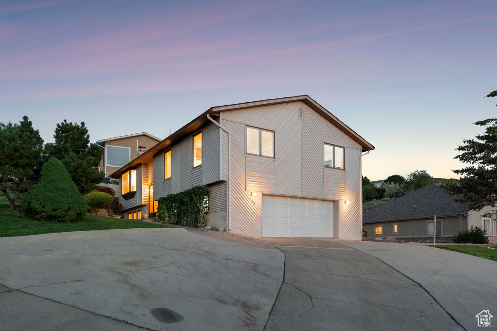 Property exterior at dusk featuring driveway and a garage