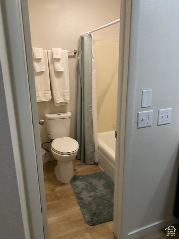 Full bath with wood finished floors, toilet, and shower / bath combo