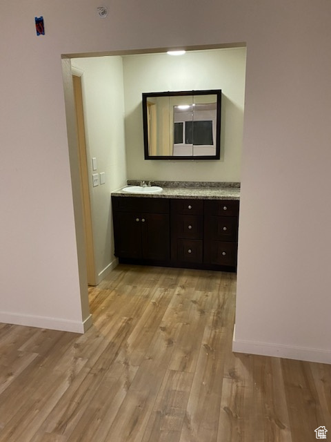Hall with light wood-style flooring, baseboards, and a sink