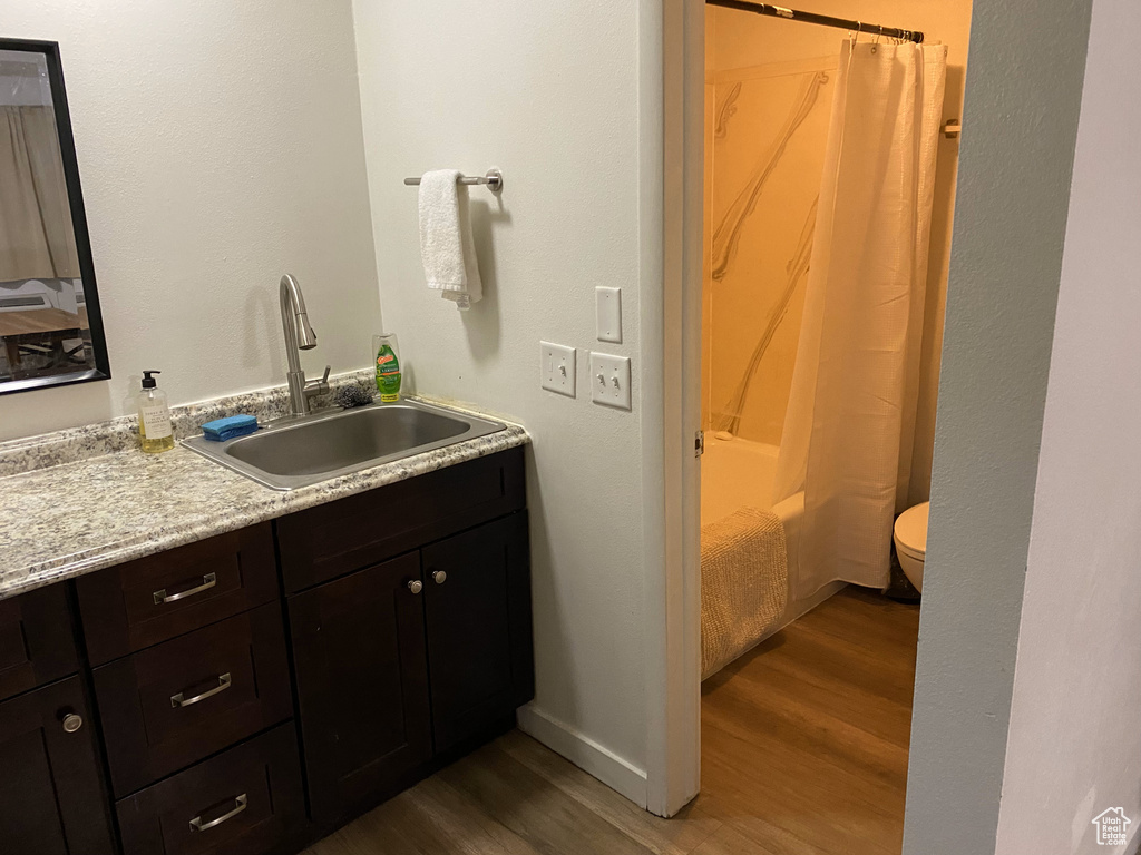 Bathroom featuring wood finished floors, vanity, toilet, and shower / bath combo