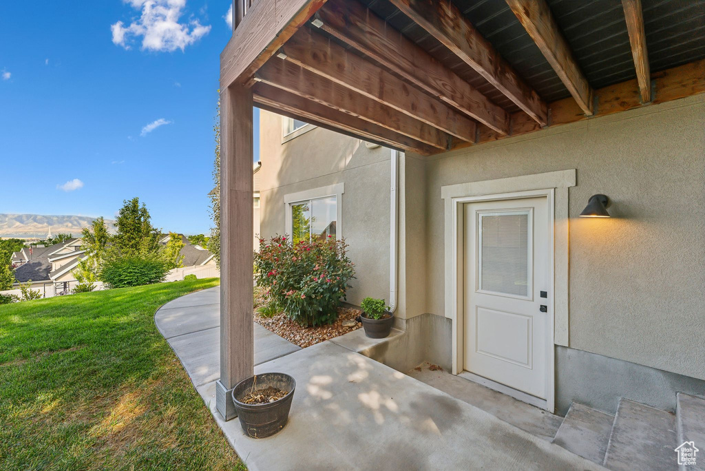 View of exterior entry featuring stucco siding, a yard, and a patio area