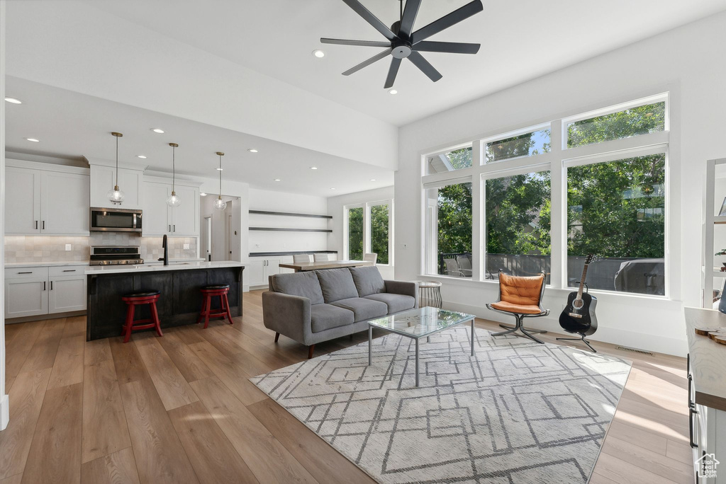 Living area with ceiling fan, light wood-style flooring, and recessed lighting