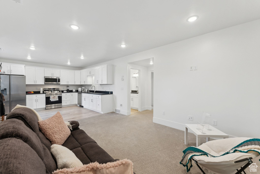 Living area with baseboards, recessed lighting, and light carpet