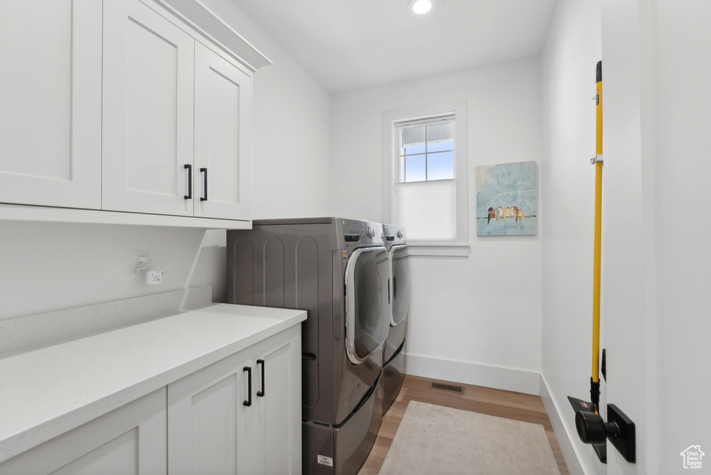 Laundry room featuring cabinet space, washing machine and clothes dryer, baseboards, light wood-type flooring, and recessed lighting