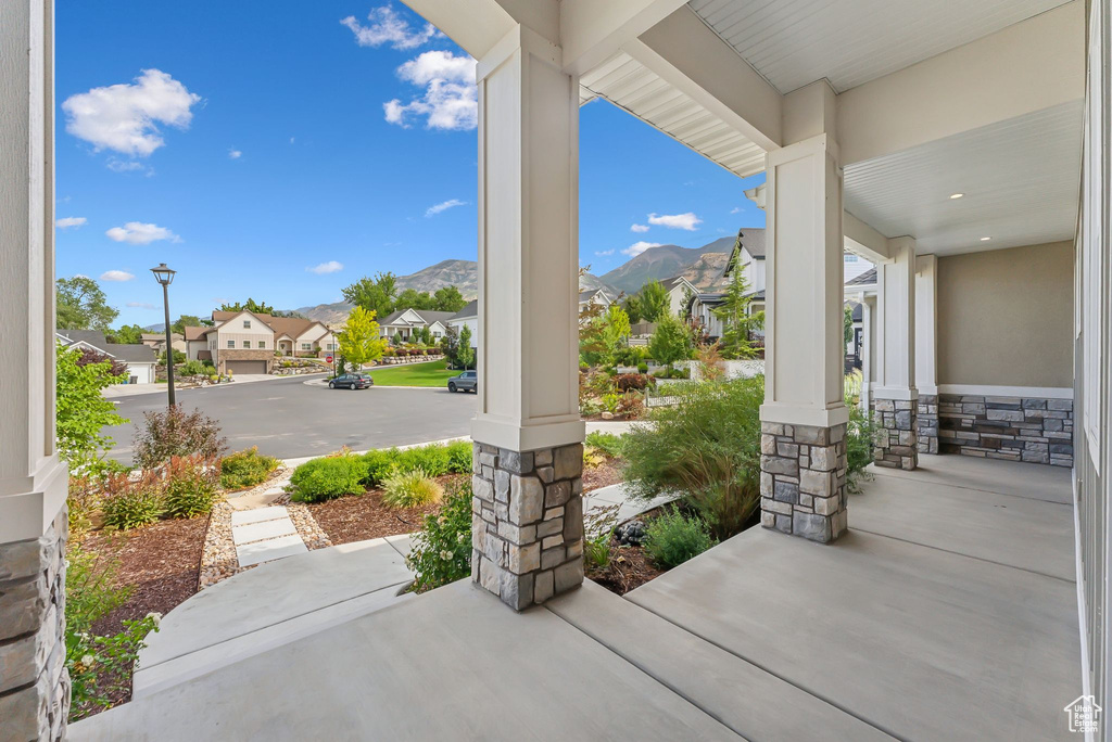 Covered porch with a residential view and a mountain view