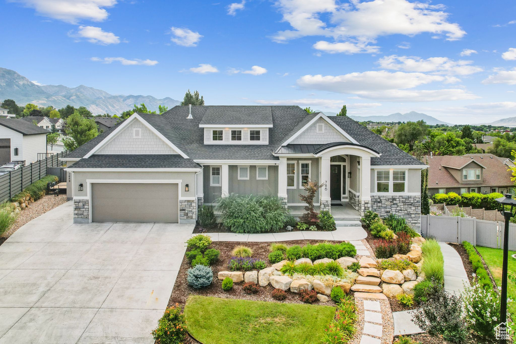 View of front of home with stone siding, a mountain view, an attached garage, driveway, and a shingled roof