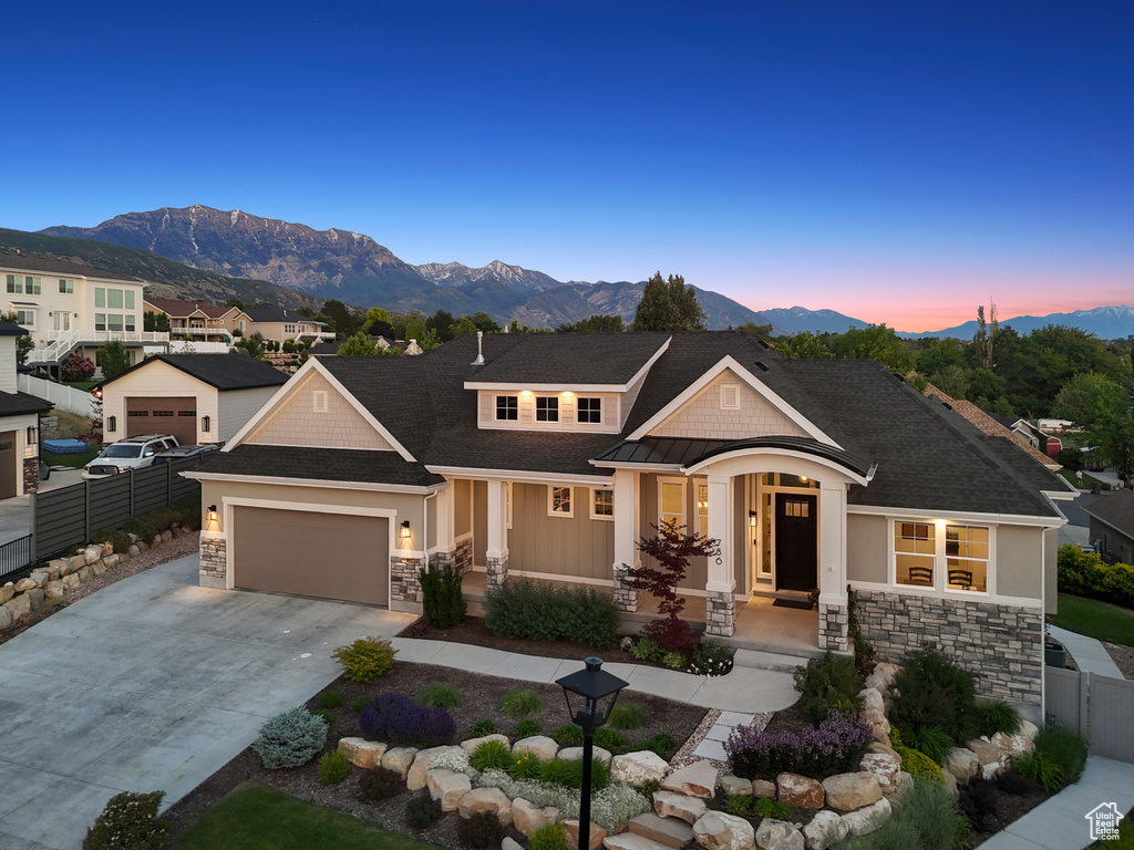 View of front facade with stone siding, a mountain view, concrete driveway, and a garage