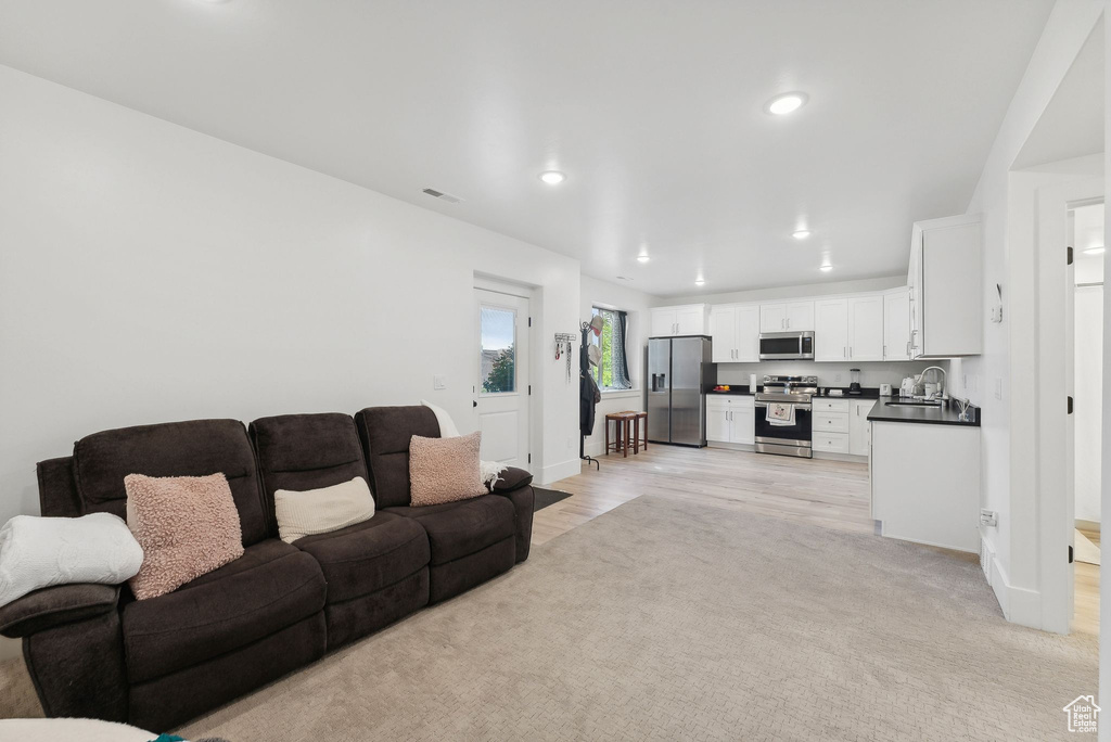 Living area with recessed lighting, baseboards, light wood finished floors, and light carpet
