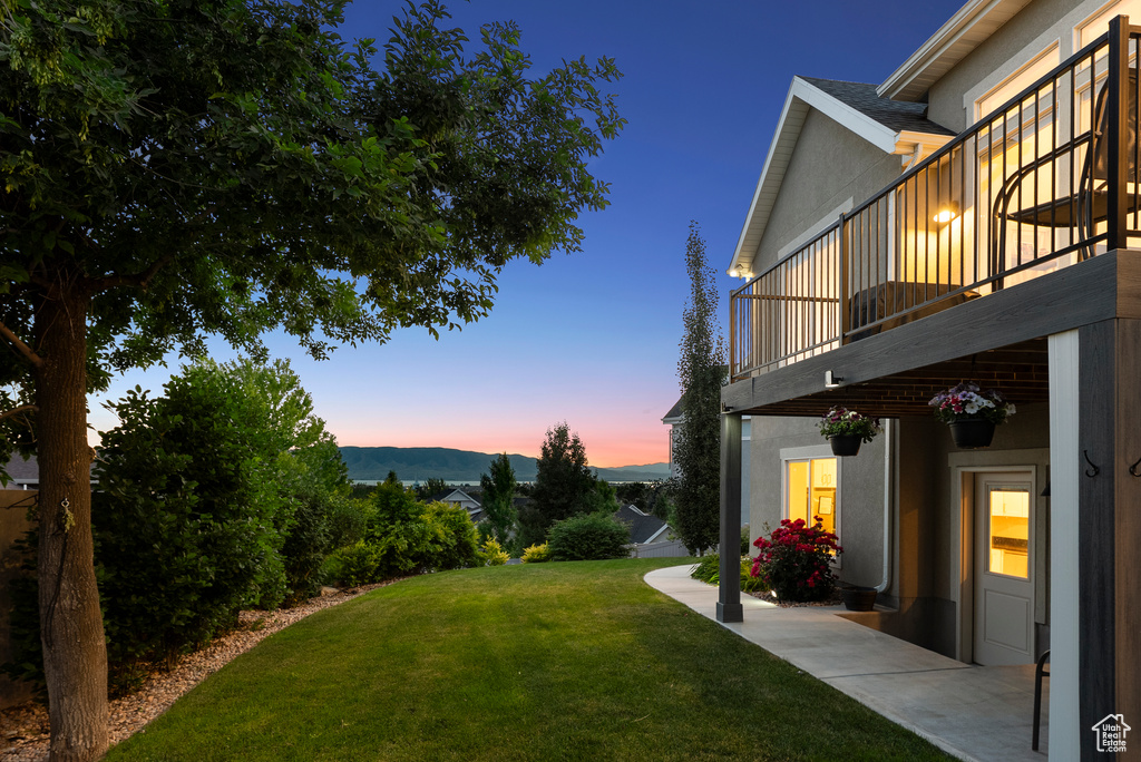 View of grassy yard featuring a balcony