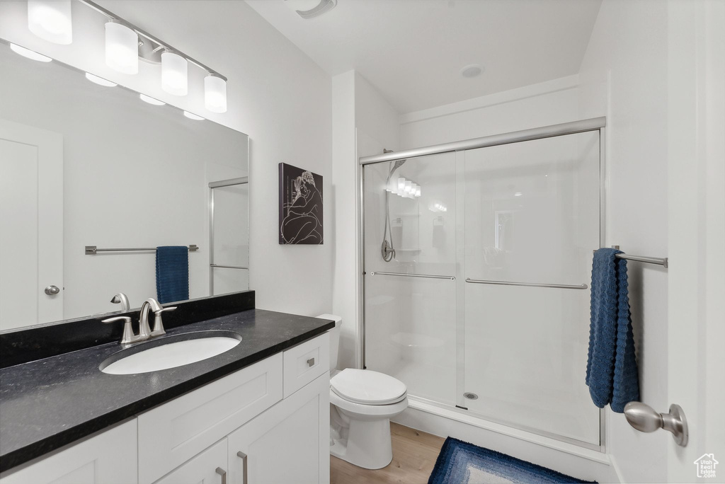 Full bath with a shower stall, vanity, toilet, and wood finished floors