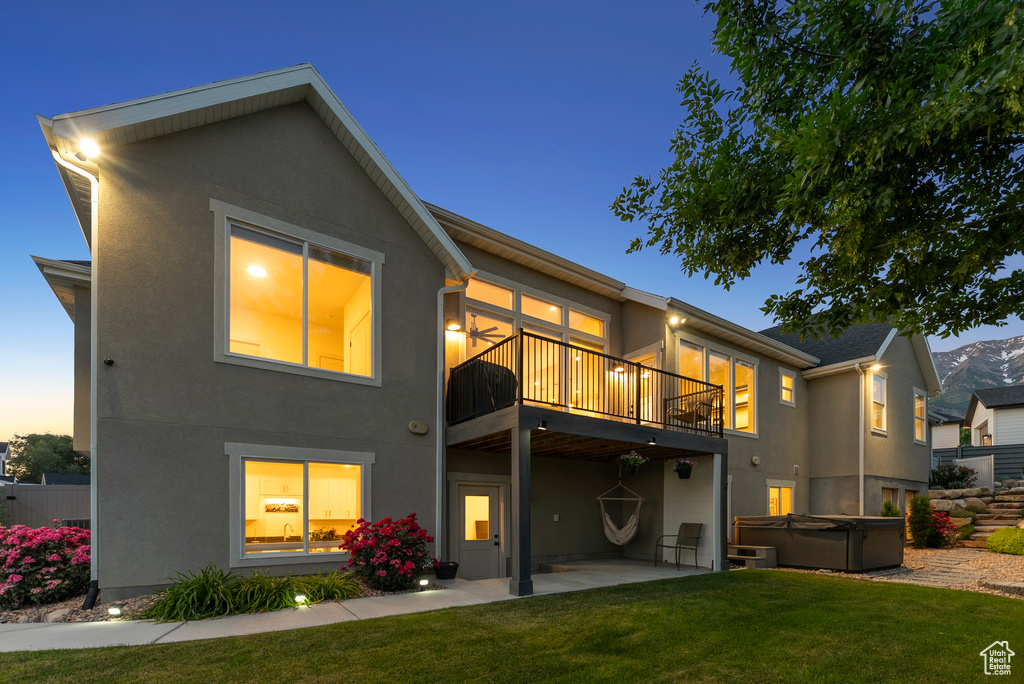 Back of house featuring a hot tub, stucco siding, and a patio area