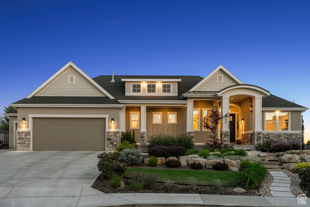 Craftsman-style home with stone siding, an attached garage, and covered porch