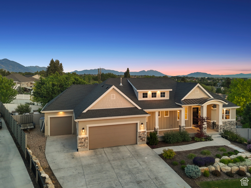 Craftsman-style house featuring stone siding, an attached garage, a mountain view, and driveway