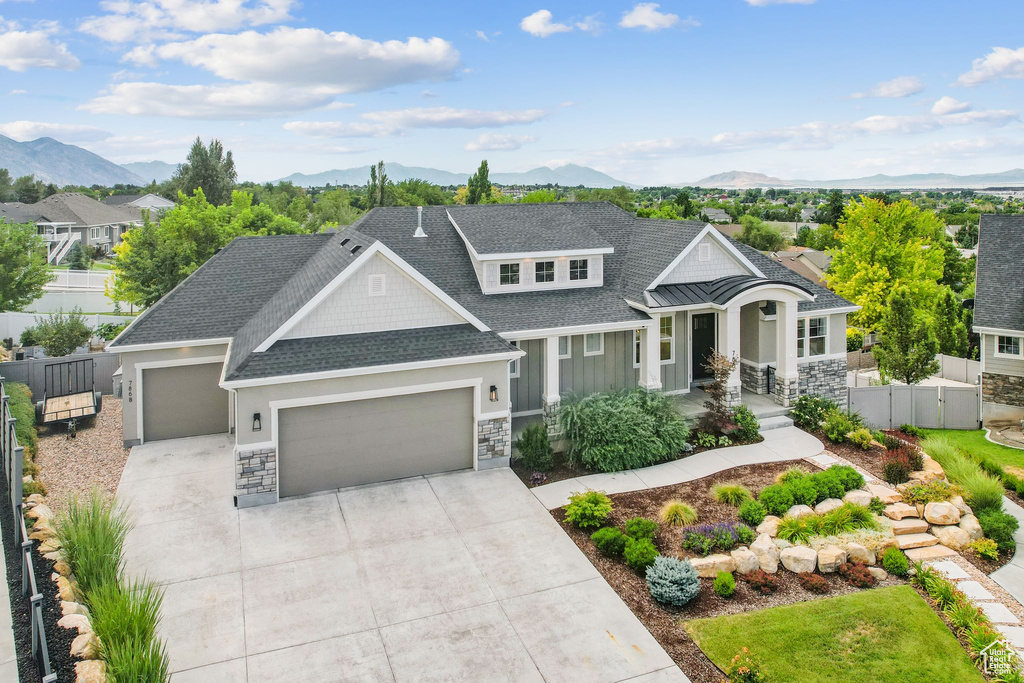View of front of house with a garage, stone siding, a mountain view, and concrete driveway