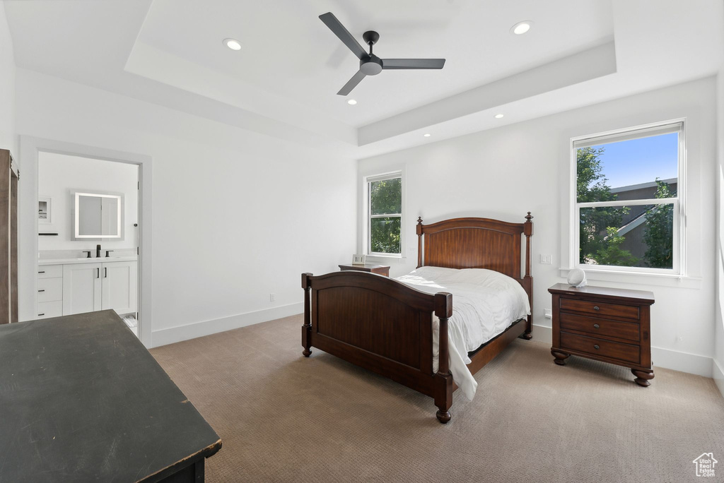 Bedroom with a raised ceiling, multiple windows, baseboards, light carpet, and recessed lighting