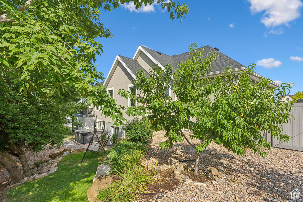 View of side of home with a shingled roof and stucco siding