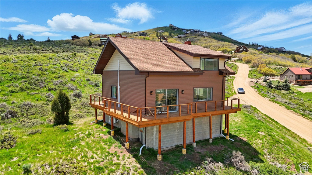 Back of house with a deck with mountain view and dirt driveway