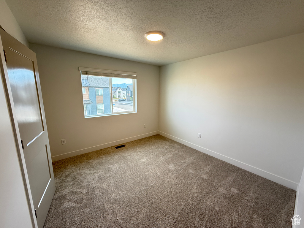 Spare room with carpet flooring, baseboards, and a textured ceiling