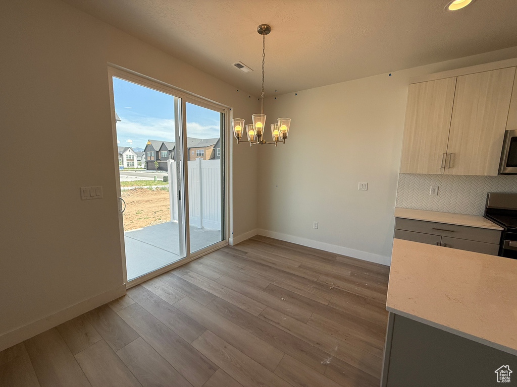 Unfurnished dining area with baseboards, a chandelier, wood finished floors, and recessed lighting