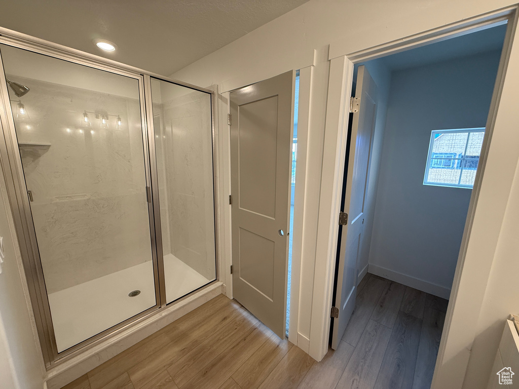 Full bath with wood finished floors, a shower stall, recessed lighting, and baseboards