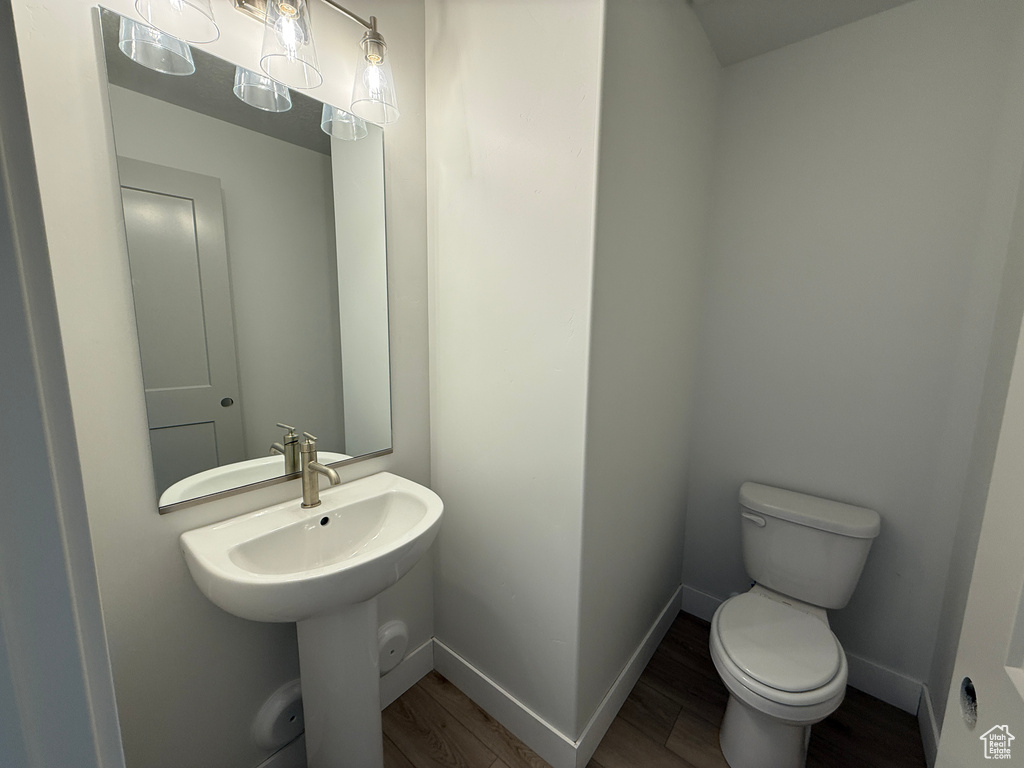 Bathroom featuring toilet, wood finished floors, a sink, and baseboards