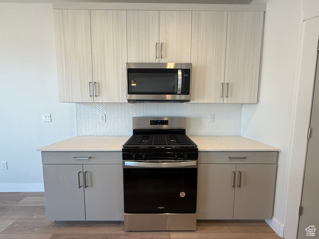 Kitchen featuring stainless steel appliances, gray cabinets, and backsplash