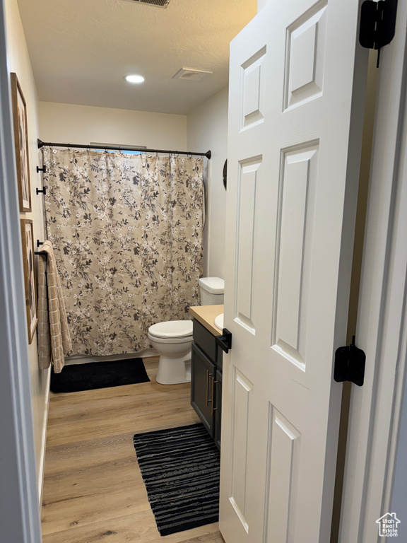 Bathroom featuring wood finished floors, toilet, vanity, a shower with curtain, and recessed lighting