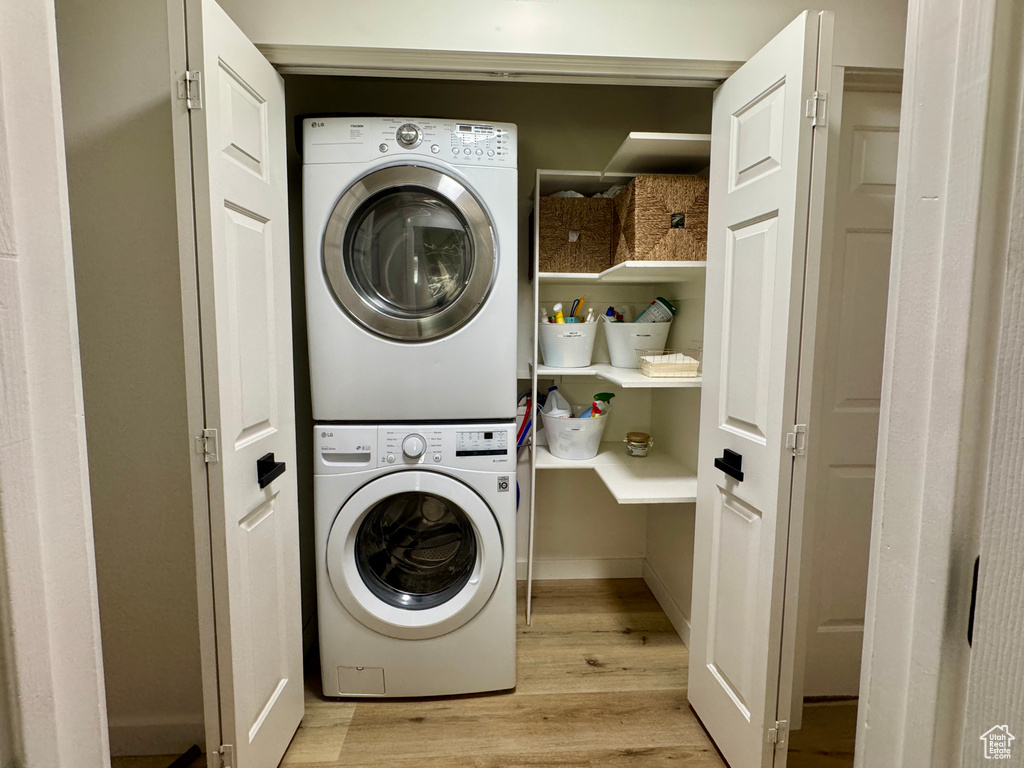 Washroom featuring stacked washing machine and dryer and light wood-style floors