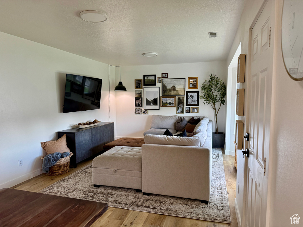 Living area featuring wood finished floors, baseboards, and a textured ceiling