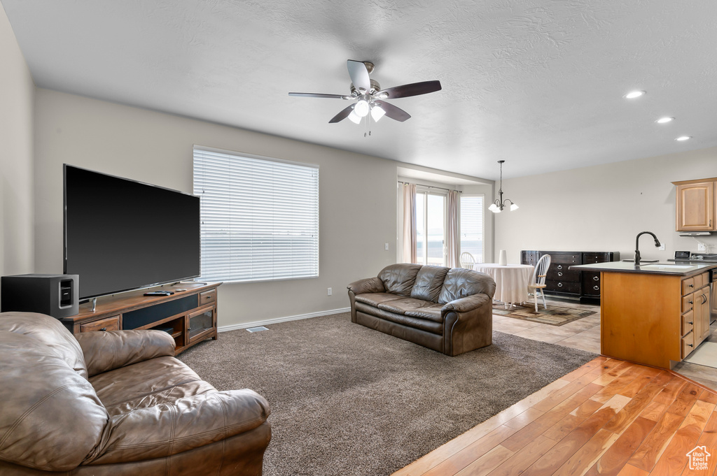 Living area featuring a ceiling fan, baseboards, recessed lighting, and light wood finished floors
