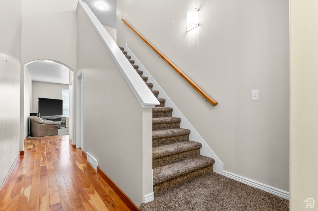 Staircase featuring arched walkways, hardwood / wood-style flooring, and baseboards