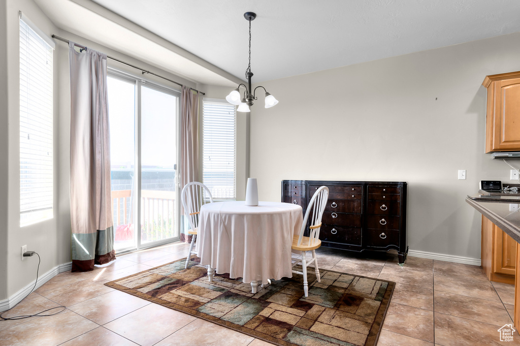 Dining area with baseboards, light tile patterned flooring, and a chandelier