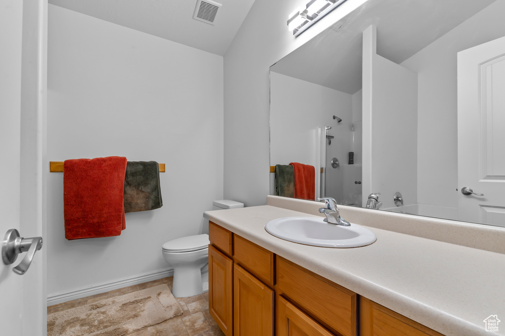 Full bathroom with vanity, a shower, toilet, baseboards, and stone finish flooring