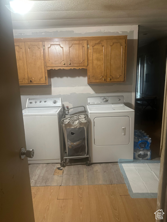 Laundry area featuring separate washer and dryer, light wood-style flooring, and cabinet space