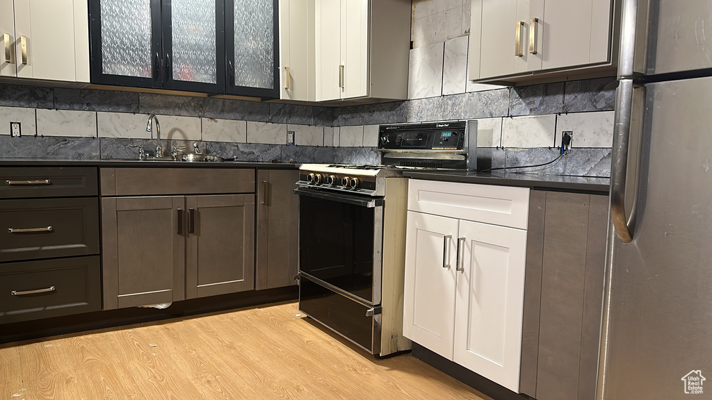 Kitchen with black range oven, freestanding refrigerator, dark countertops, and a sink