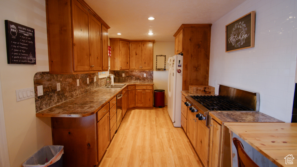 Kitchen with stainless steel appliances, a sink, light wood finished floors, recessed lighting, and decorative backsplash